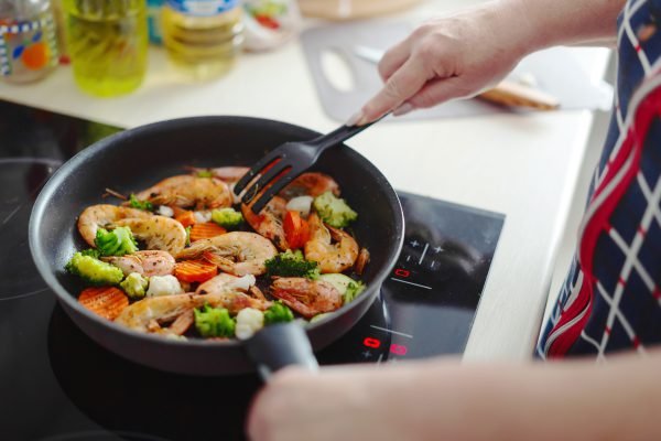 woman staying home kitchen cooking shrimps with vegetables pan home cooking healthy cooking concept
